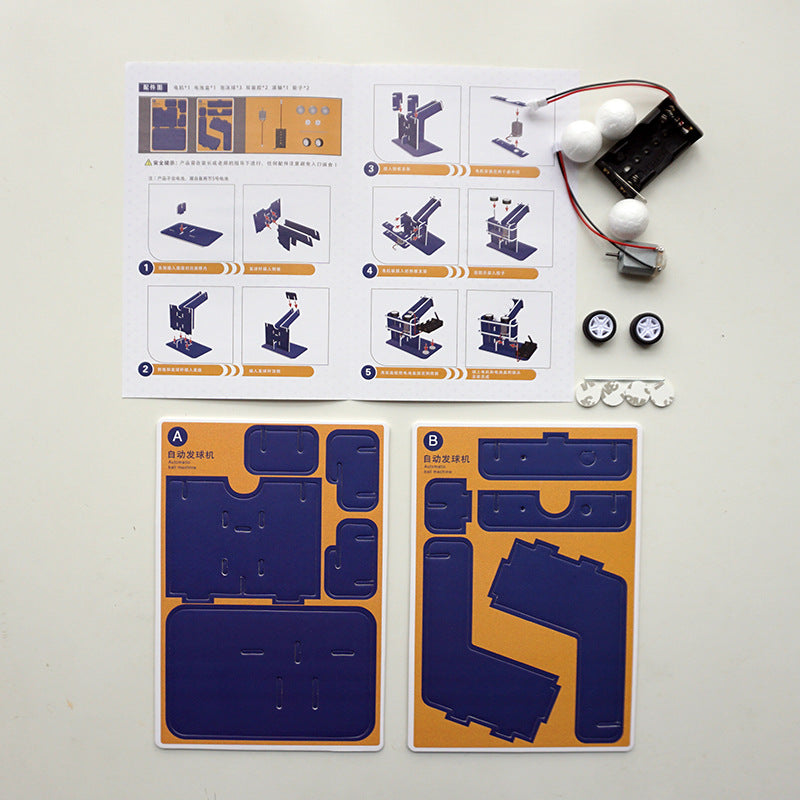 DIY Automatic Ball Launcher Kit: Cardboard parts, motors, and assembly tools laid out.