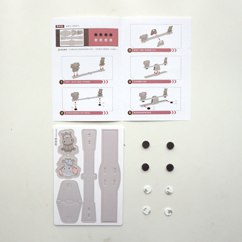 Contents of DIY Seesaw Kit: pre-cut cardboard pieces, magnetic weights, and detailed instruction manual for easy assembly.