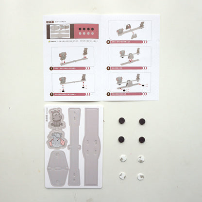 Contents of DIY Seesaw Kit: pre-cut cardboard pieces, magnetic weights, and detailed instruction manual for easy assembly.