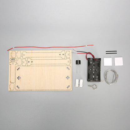 DIY CrossFire Kit components laid out: laser-cut wooden pieces, battery holder, wires, diodes, and metal maze wire for STEM education.